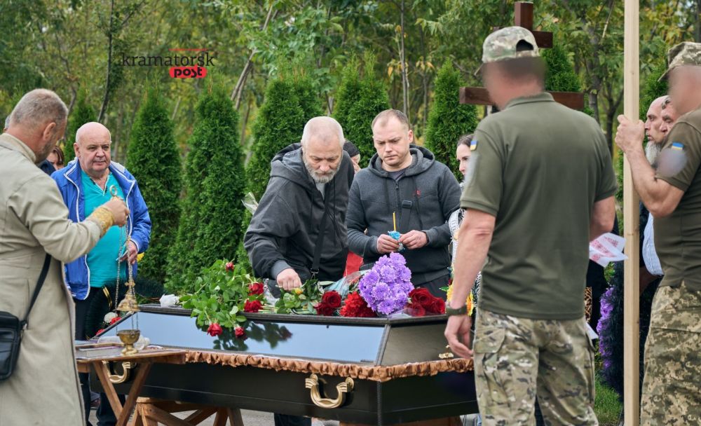 старший чоловік покладає квіти на труну загиблого воїна