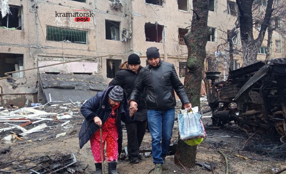 чоловіки допомогають пересуватися мешканці пошкодженого будинку у Краматорську