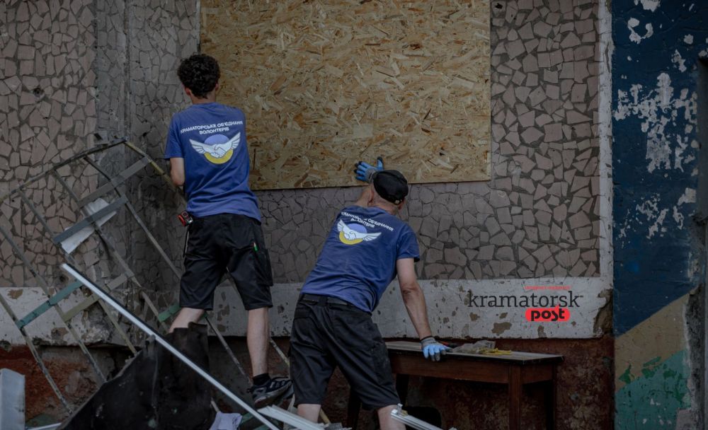 Волонтери закривають фанерою вибиті вікна у пошкодженому будинку